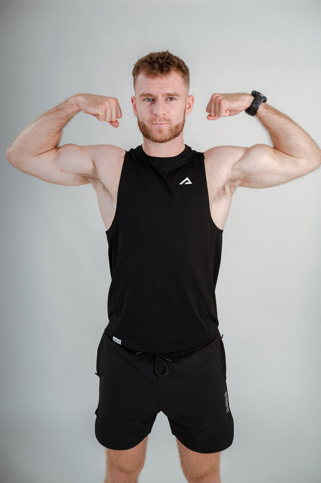 Athlete flexing wearing StagFit black drop arm tank top.