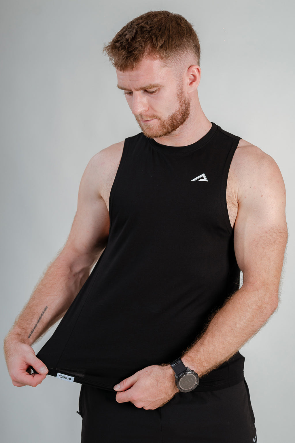 StagFit Performance drop arm tank top black — athlete stretching the fabric.