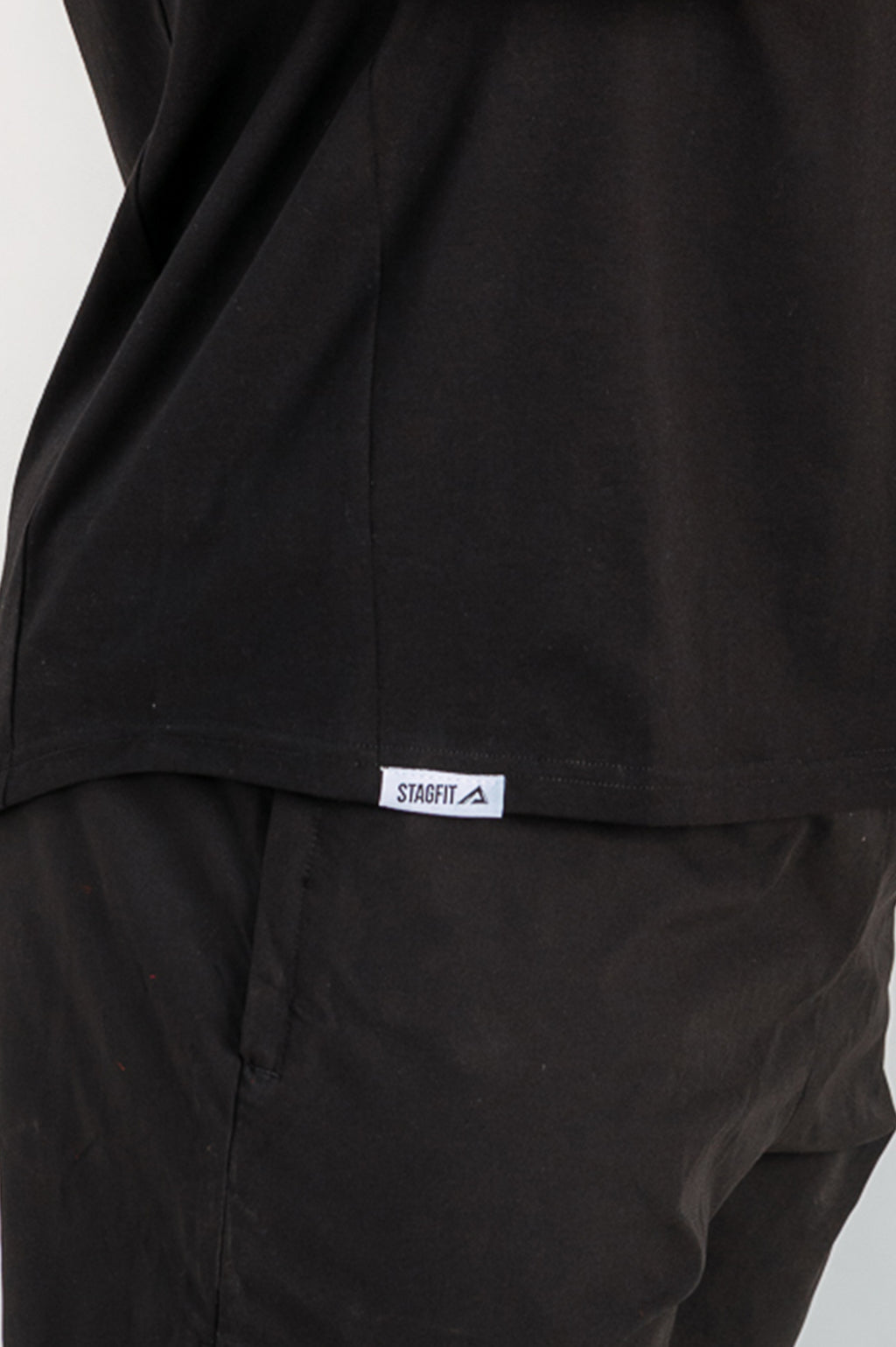 Close-up of StagFit drop arm tank top fabric and hem tag.