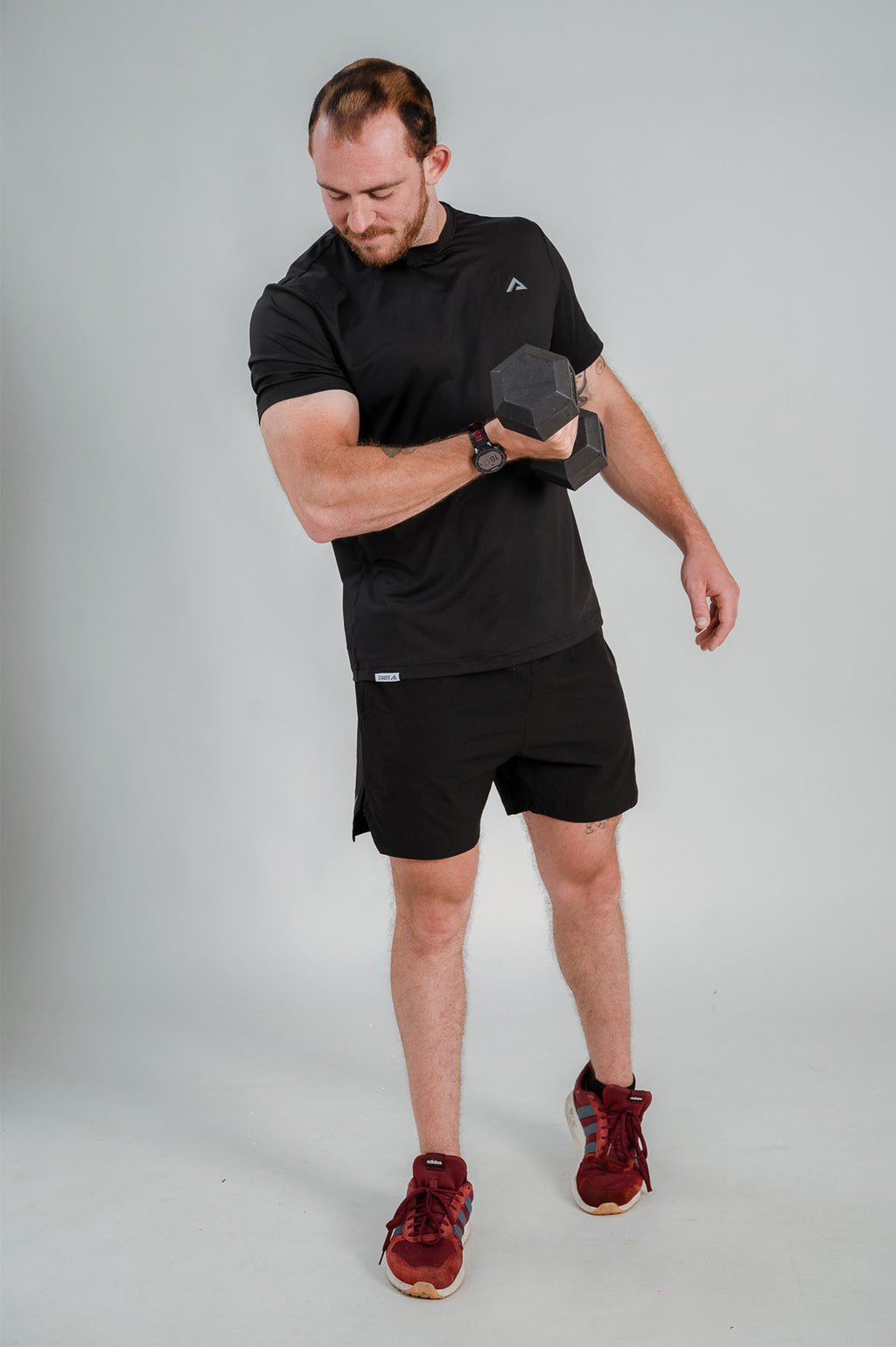 Model lifting a dumbbell wearing StagFit black t-shirt.